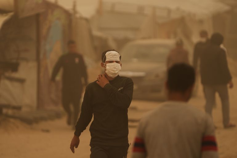 A Palestinian man wearing a face mask walks through a sandstorm in Khan Younis, southern Gaza Strip, Saturday, March 14, 2026. (AP Photo/Abdel Kareem Hana)