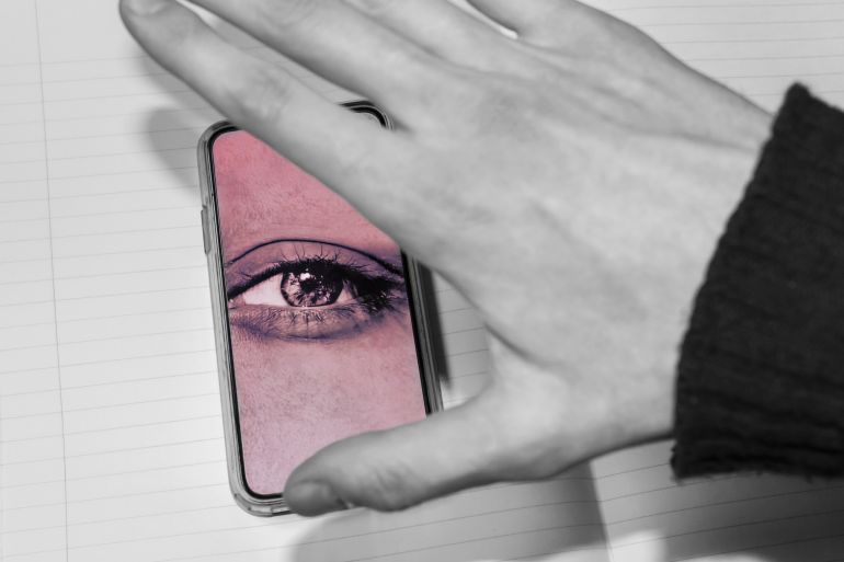 apps6-1774856614 hand trying to close the screen of the smartphone with watching eye. smartphone is spying on the user. Smartphones overhear and spy, selective focus