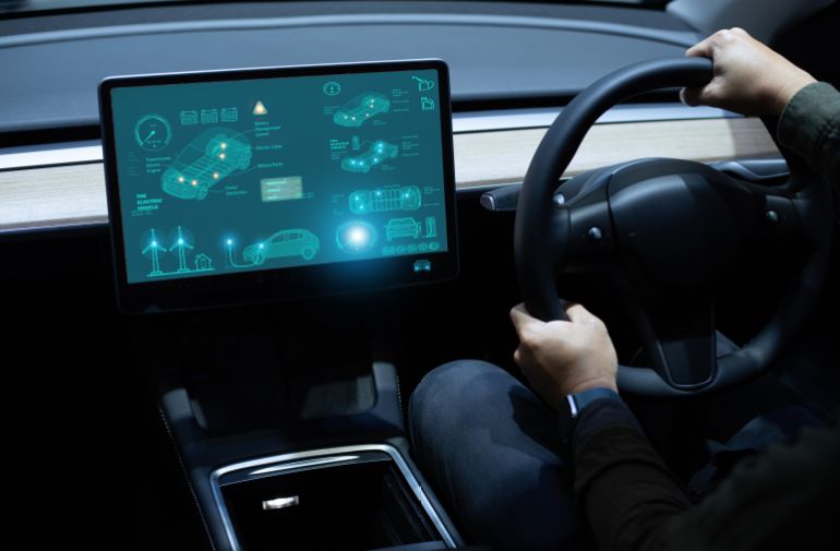 Person driving with futuristic electric vehicle dashboard display highlighting car features.