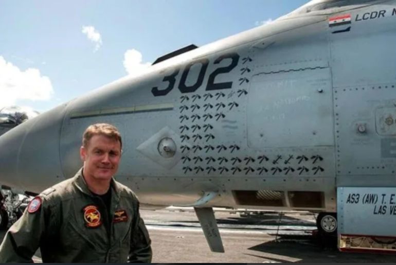 d8b33-1774673052 الملازم مايكل تريمل يقف إلى جانب المقاتلة على متن حاملة الطائرات يو إس إس جورج إتش دبليو بوش في 2018 (الجيش الأمريكي)