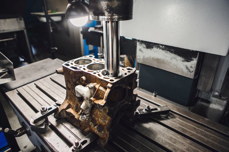 Engine cylinder boring on cnc machine. Boring under the piston after engine sleeve using machine with Computer Numerical Control. Repair and elimination of engine score.