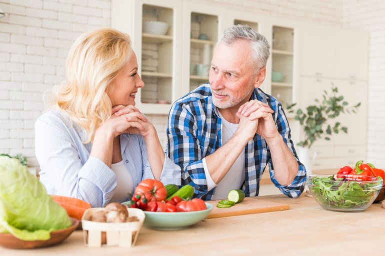 Portrait of a senior couple leaning on wooden table looking at each other @فري بيك