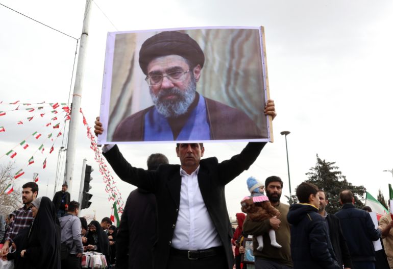 epa_69a3ff0815c9-1772355336 epa12726144 An Iranian man holds a picture of Mojtaba Khamenei, the son of the Iranian Supreme Leader, as he takes part in celebrations of the 47th anniversary of the Islamic Revolution in Tehran, Iran, 11 February 2026. The Islamic Republic marks the anniversary of the 1979 revolution, which toppled the monarchy and established the Islamic Republic of Iran, with Ayatollah Ruhollah Khomeini serving as its first Supreme Leader. EPA/ABEDIN TAHERKENAREH