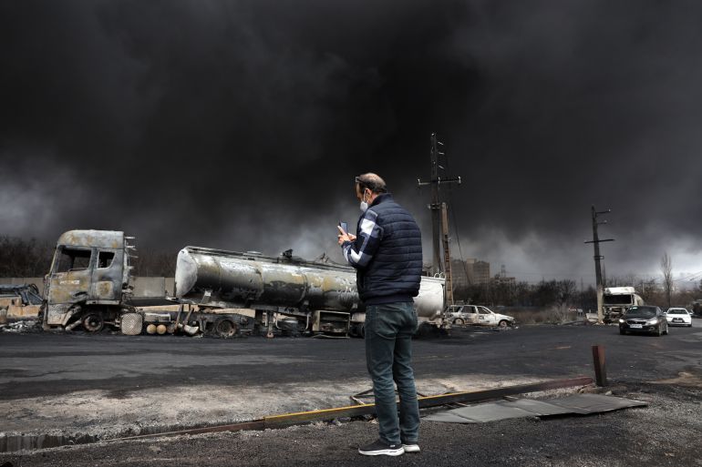 epa_69bee6864050-1774118534 epa12803464 An Iranian man looks as smoke still rises from Shahran Oil Refinery following last night airstrike in Tehran, Iran, 08 March 2026. A joint Israeli and US military operation continues to target multiple locations across Iran since the early hours of 28 February 2026. EPA/ABEDIN TAHERKENAREH