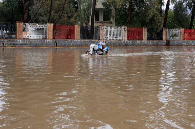epa12855049 People ride a motorcycle along a flooded street following heavy rainfall in Sana'a, Yemen, 27 March 2026. Heavy rains and flooding have hit Sana'a and most parts of Yemen, according to Yemen's meteorological service. EPA/YAHYA ARHAB