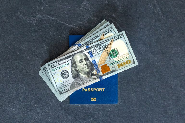 Biometric passport with money. Passport and dollars. Emigration concept. High quality photo. International currency. Passport with money on colored background, top view. t المصدر: فريبيك