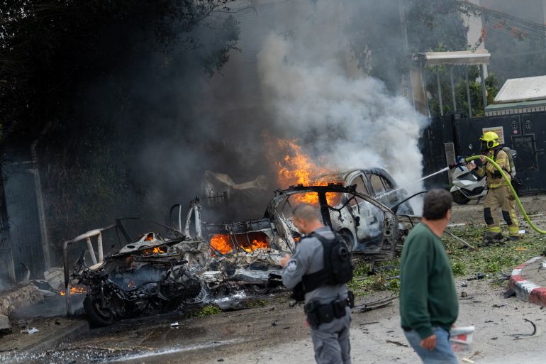 getty_69b6aae8ed-1773578984-1 TEL AVIV, ISRAEL - MARCH 15: A firefighter works to extinguish vehicles set ablaze by fragments from the impact of an Iranian projectile on March 15, 2026 in Tel Aviv, Israel. Iran has continued firing waves of drones and missiles at Israel after the United States and Israel launched a joint attack on Iran early on February 28th. (Photo by Erik Marmor/Getty Images)
