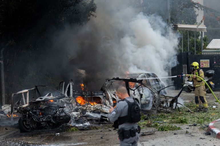 TEL AVIV, ISRAEL - MARCH 15: A firefighter works to extinguish vehicles set ablaze by fragments from the impact of an Iranian projectile on March 15, 2026 in Tel Aviv, Israel. Iran has continued firing waves of drones and missiles at Israel after the United States and Israel launched a joint attack on Iran early on February 28th. (Photo by Erik Marmor/Getty Images)