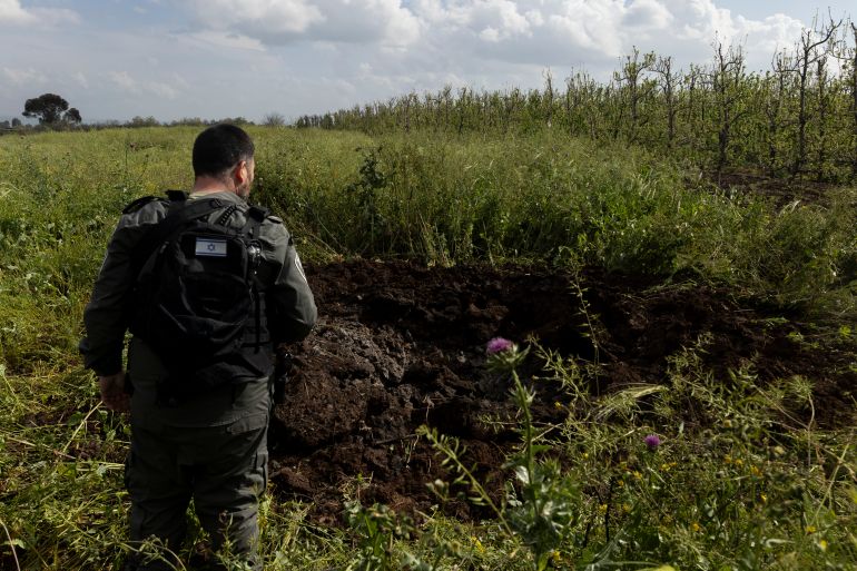 getty_69bd6c27e6-1774021671 NORTHERN ISRAEL, ISRAEL - MARCH 20: An Israeli police officer inspects a crater left by a rocket strike in a roadside field, after it was launched from Lebanon on March 20, 2026 in Northern Israel, Israel. Israel and Hezbollah have continued exchanging hostilities across Israel's northern border with Lebanon, after the Iran-backed militant group began launching missiles at Israel on March 2, in what it said was retaliation for the joint U.S.-Israeli war on Iran. (Photo by Amir Levy/Getty Images)