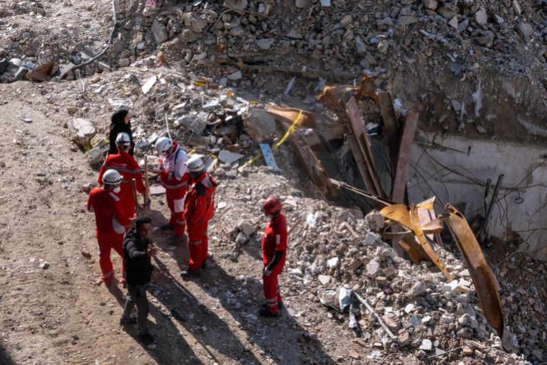 getty_69beeee029-1774120672 TEHRAN, IRAN - MARCH 21: Civilians and emergency workers stand near the remains of a residential and commercial building on March 21, 2026 in the Shahrak-e Gharb neighbourhood of Tehran, Iran. The building was hit on March 16 amid U.S. and Israeli attacks and resulted in several civilian deaths and missing persons. The United States and Israel have continued their joint attack on Iran that began on February 28. Iran has retaliated by firing waves of missiles and drones at Israel, and targeting U.S. allies in the region. (Photo by Majid Saeedi/Getty Images)