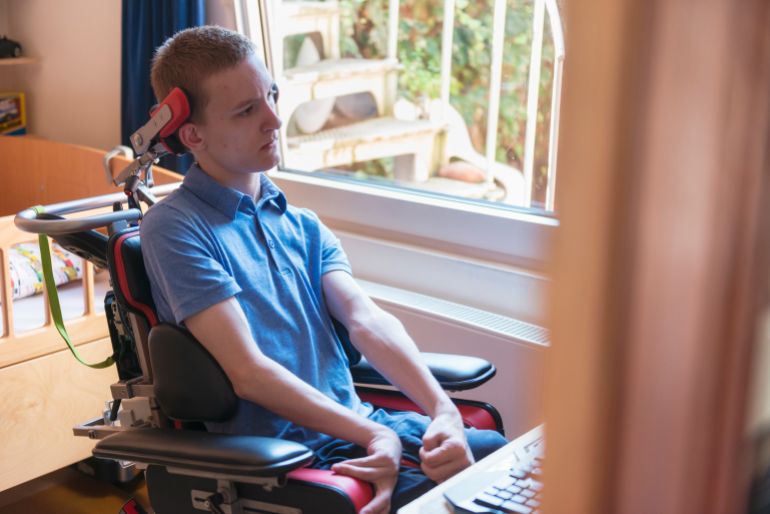 التصلب الجانبي الضموري Color image of a real life young physically impaired ALS patient computer gaming with the help of his electronic wheelchair.