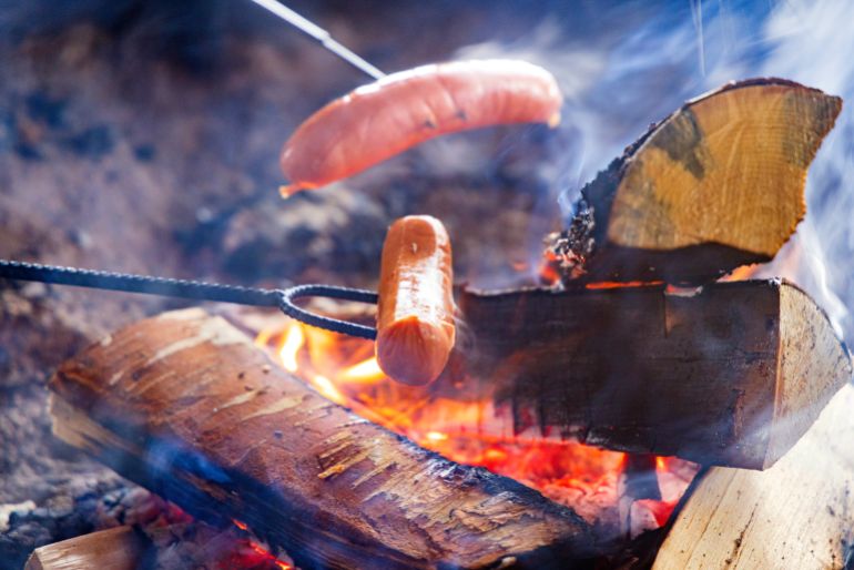 gettyimages-2066858868-1773520607 هوت دوغ Campfire cooking sausages on stick