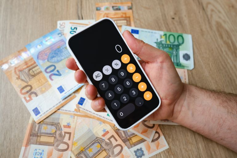Tallinn, Estonia - December 29, 2021: iPhone is open in the calculator application and lies on the money. Cash in euros for payment or exchange. A man calculates his salary in euro banknotes