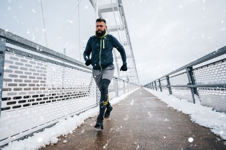 Handsome middle age man with a beard running and exercising outside on extremely cold and snowy day. Sport and fitness motivation theme.; Shutterstock ID 2214198093; purchase_order: ajnet; job: ; client: ; other: