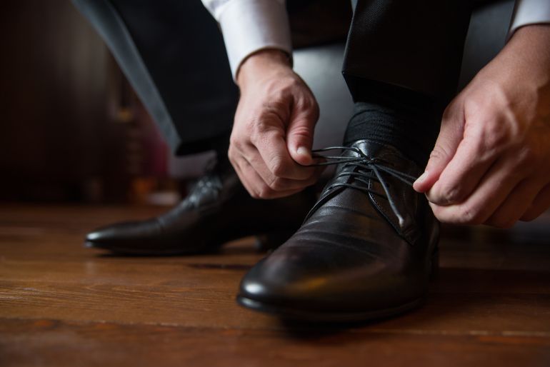 the groom puts on wedding shoes before the ceremony