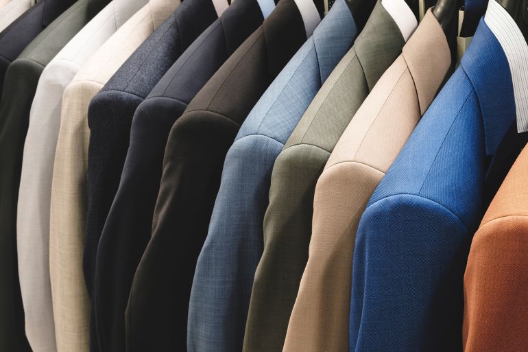 Row of men's suits hanging. Elegant jacket hanged on a clothes rack.; Shutterstock ID 2435685053; purchase_order: aj; job: ; client: ; other: