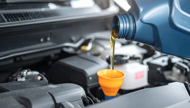 Close-up of engine oil being poured into a car engine via a funnel. Maintenance and repair concept.
