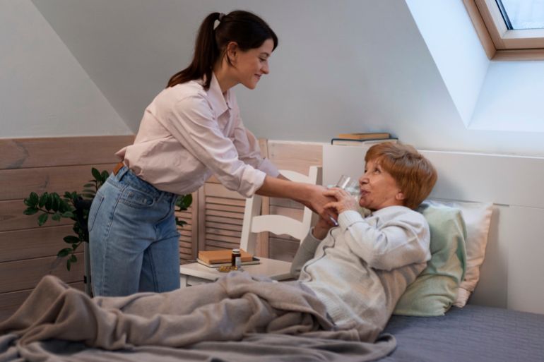 Senior woman putting a white blanket on her daughter sleeping on the sofa freepik