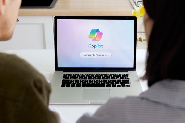 Madrid, Spain; 05 16 2025 Two colleagues are using copilot, an ai companion, on a laptop in a modern office environment