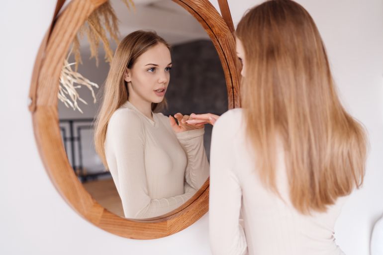 Young pretty girl at home look in mirror enjoying herself alone, no makeup natural beauty freepik