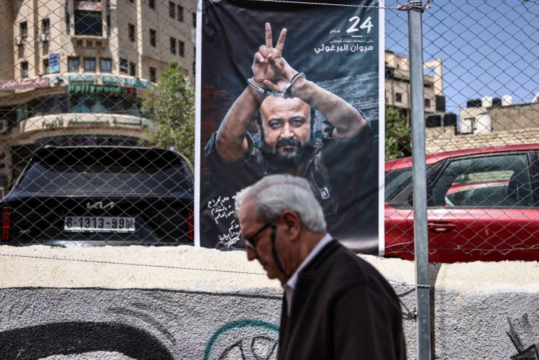 A man walks past a poster of jailed Palestinian leader Marwan Barghouti on the sidelines of a rally in Ramallah in the occupied West Bank on April 16, 2026 to mark Prisoners' Day and to protest against Israeli parliament's approval of a new death penalty bill for Palestinians convicted of deadly attacks.