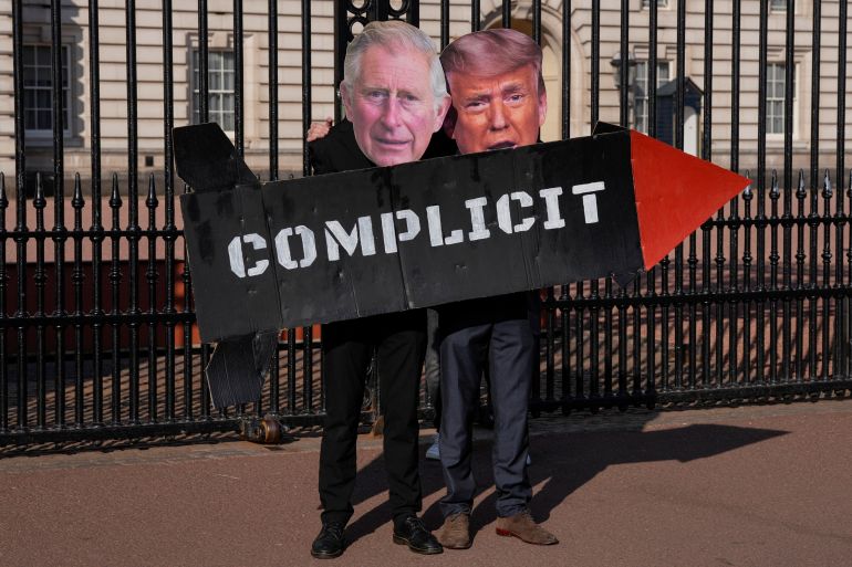 TOPSHOT - Two members of the 'Stop Trump Coalition' action group pose with a mock missile and masks of Britain's King Charles III and US President Donald Trump in front of the gates of Buckingham Palace in central London on April 27, 2026, to call for an end to the UK's support to the US in the bombing of Iran. (Photo by CARLOS JASSO / AFP)