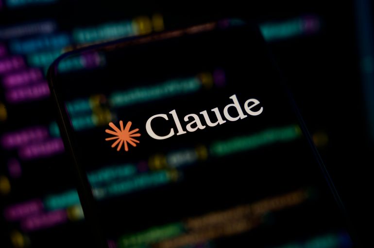 Paris, France - April 1, 2026: The Claude by Anthropic logo is displayed on a mobile phone screen placed over a computer monitor showing lines of programming code in Python and React. The composition symbolizes the intersection of artificial intelligence and software development, and the concept of "vibecoding" (AI-assisted coding).