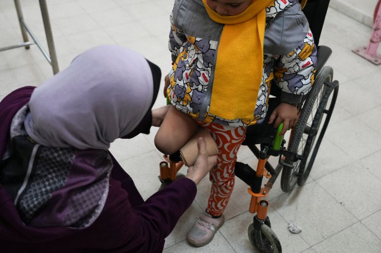 Five-year-old Palestinian Sila Abu Aqlan sits on her wheelchair as a doctor adjusts the cover on her right amputated leg at the Artificial Limbs and Polio Center in Gaza City, on Wednesday, Feb. 26, 2025, (AP Photo/Abdel Kareem Hana)