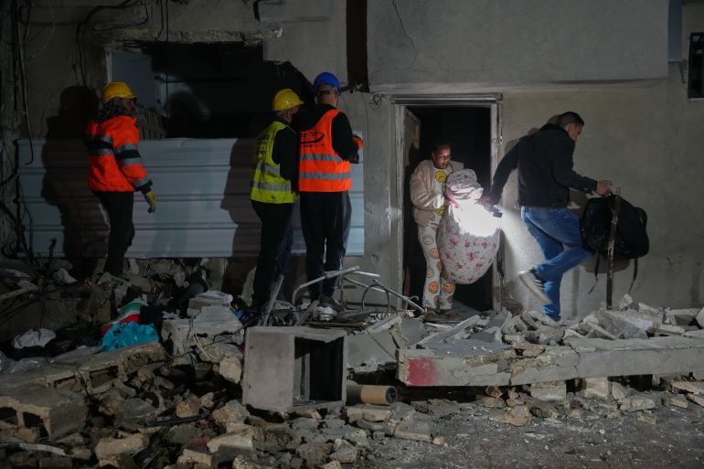Residents carry personal belongings as they leave a building damaged in a missile strike in Tel Aviv, Israel, early Saturday, March 28, 2026. (AP Photo/Maya Levin)