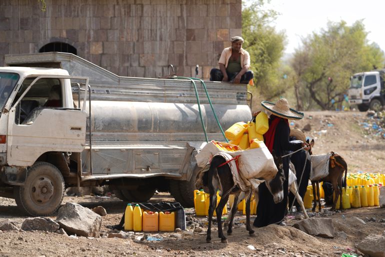 A local resident collects water from a distribution truck at a makeshift camp for displaced people near Taiz, Yemen, Friday, March 13, 2026. (AP Photo/Abdulnasser Alseddik)