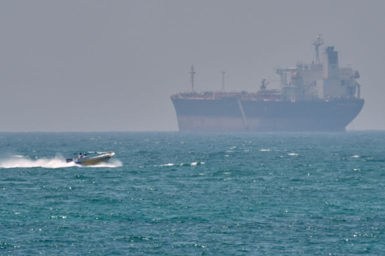 A boat sails past a tanker anchored on the Strait of Hormuz off the coast Qeshm island, Iran, Saturday, April 18, 2026. (AP Photo/Asghar Besharati)