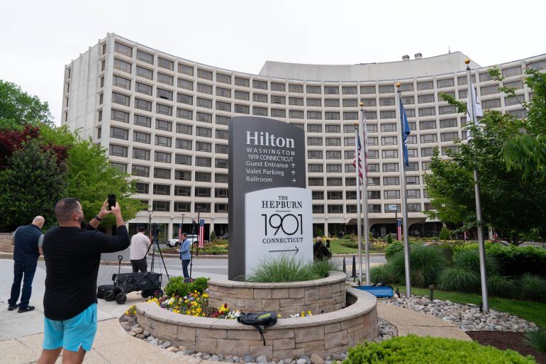ap_69eed18294180-1777258882 A man takes a picture of the Washington Hilton Hotel, Sunday, April, 26, 2026, in Washington, the day after a gunman tried to storm into the hotel's ballroom during the White House Correspondents’ Dinner. (AP Photo/Jose Luis Magana)