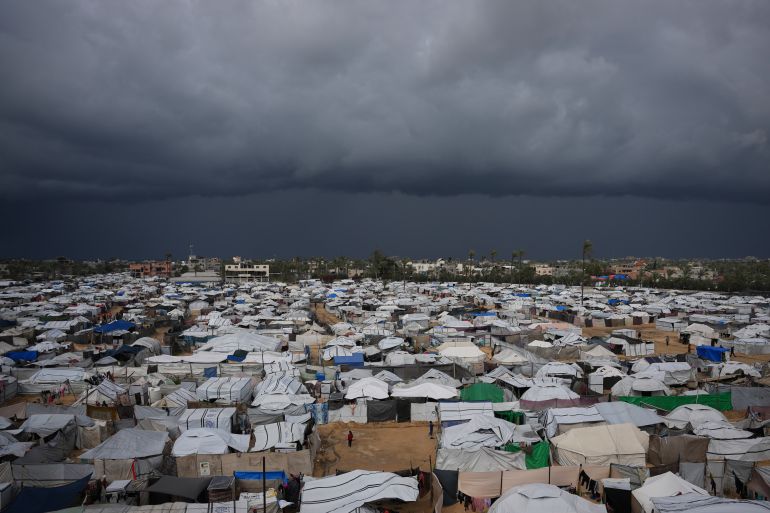 FILE - Palestinian children stand on an area surrounded by makeshift tents in a camp for displaced people in Deir al-Balah, central Gaza Strip, Saturday, Dec. 27, 2025. (AP Photo/Abdel Kareem Hana, File)