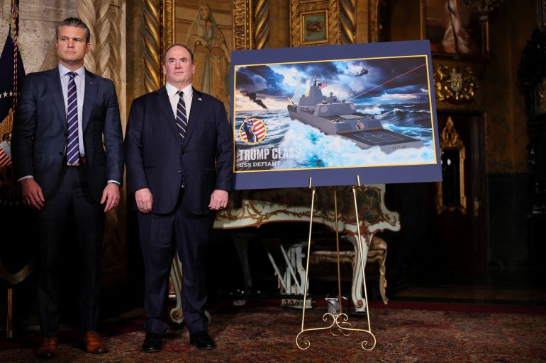 FILE PHOTO: U.S. Secretary of Defense Pete Hegseth and Secretary of the Navy John Phelan stand by a rendering of the 'Trump Class' USS Defiant, as they listen to President Donald Trump (not pictured) make an announcement about the Navy's "Golden Fleet", at Mar-a-lago in Palm Beach, Florida, U.S., December 22, 2025. REUTERS/Jessica Koscielniak/File Photo
