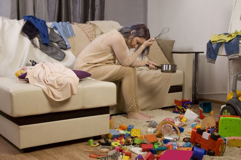 Mother sitting on the couch. Mom tired to tidy up the house. Child scattered toys. Children's room. Mess in the house