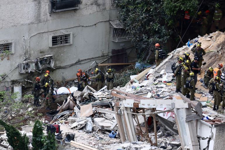 epa_69d3fc18e2c1-1775500312 epa12871406 Israeli rescue teams carry a covered body as they search the site of a residential building hit by an Iranian missile strike in Haifa, Israel, 06 April 2026. Magen David Adom (MDA) reported that the deceased bodies of four people previously listed as missing have been recovered. EPA/JAMAL AWAD