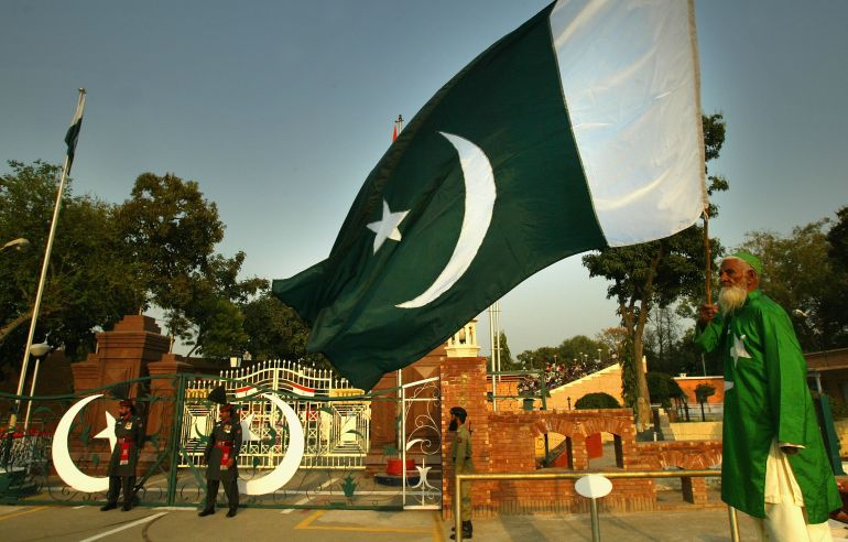 WAGAH, PAKISTAN - MARCH 11: A man waves the flag of Pakistan before the ceremony to lower the national flags at the border crossing between Pakistan and India March 11, 2004 in Wagah, Pakistan. The ceremony, a daily colourful parade conducted by Pakistani Patan guards and the Indian Border Security force took place as the Indian cricket team were beginning their first full tour of Pakistan in almost 15 years. The tour is seen as evidence that the two nuclear-armed rivals are getting closer after almost going to war over the Himalayan region of Kashmir less than two years ago. (Photo by Scott Barbour/Getty Images) *** Local Caption ***
