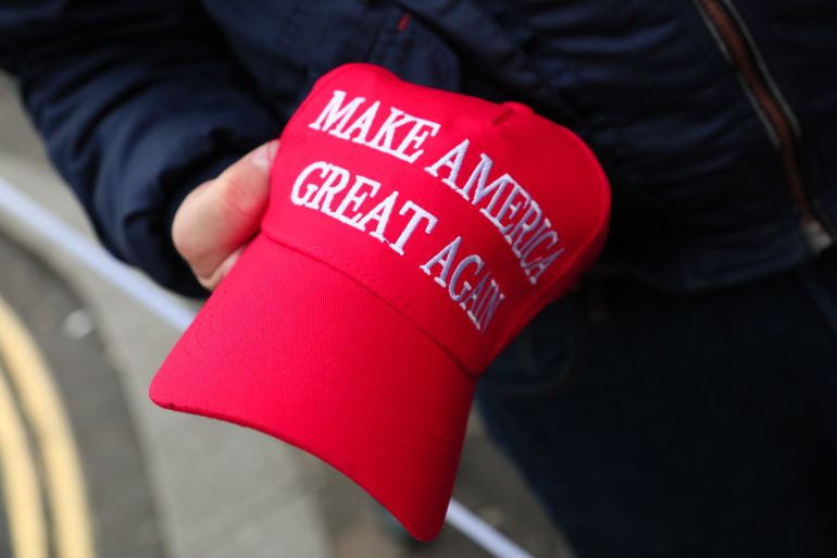 LONDON, ENGLAND - JANUARY 18: A man holds a MAGA hat as demonstrators march from BBC Broadcasting House to Downing Street during the "National March for a Free Iran" on January 18, 2026 in London, England. Demonstrators are marching from the BBC to Downing Street, calling on the UK government to proscribe Iran's Islamic Revolutionary Guard Corps (IRGC), shut the Iranian Embassy in London, and end diplomatic ties with Iran. Protests that arose in Iran in December in response to the country's economic crisis have seemingly ebbed following a violent crackdown by Iranian security forces. (Photo by Alishia Abodunde/Getty Images)