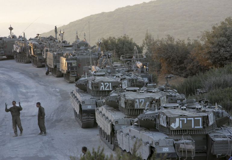 LEBANESE BORDER, ISRAEL - AUGUST 17: Israeli soldiers walk past tanks and armored personnel carriers after their return from an early morning patrol in southern Lebanon to a forward base August 17, 2006 on Israel's border with Lebanon. Israel is consolidating its positions in southern Lebanon, bringing its troops closer to its border, as Lebanese troops, backed by tanks and armored vehicles, began to deploy south of the Litani River in line with a United Nations cease-fire plan to end fighting between Israel and Hezbollah. (Photo by David Silverman/Getty Images)