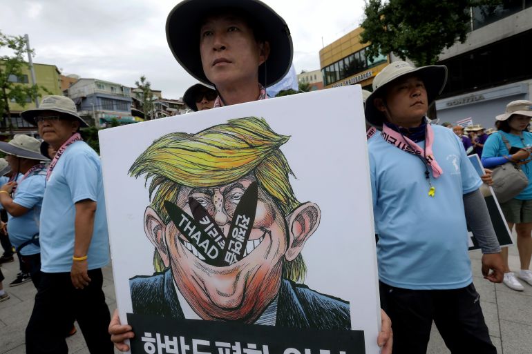 SEOUL, SOUTH KOREA - AUGUST 14: A South Korean protesters holds a placard with an illustration of U.S. President Donald Trump during a rally against the deployment of the Terminal High-Altitude Area Defense (THAAD) near the U.S. army base on August 14, 2017 in Seoul, South Korea. The advanced missile system, which could intercept the short to middle range missiles, will be deployed in a small village of Seongju amid protests by environmental and anti-U.S. activists. (Photo by Chung Sung-Jun/Getty Images)