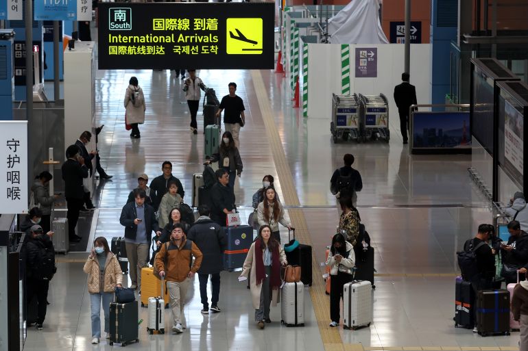 OSAKA, JAPAN - DECEMBER 04: Passengers pull their rolling suitcases through the arrivals hall at Kansai International Airport on December 04, 2025 in Osaka, Japan. More than 1,900 scheduled flights from China to Japan in December have been cancelled due to political disputes between Tokyo and Beijing over Taiwan, according to media reports. Chinese tourist arrivals to Japan will be reduced by more than half due to flight cancellations and following Beijing's call for citizens to avoid traveling to Japan. Kansai International Airport officials announced weekly flights on China routes will drop from a planned peak of 525 to 348 by the second week of December, a decline of 34 percent. (Photo by Buddhika Weerasinghe/Getty Images)