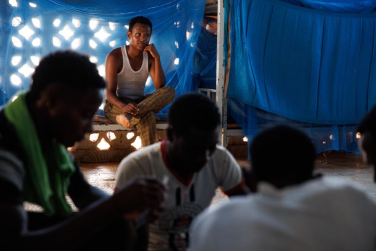 OBOCK, DJIBOUTI - JANUARY 18: A man watches others interact inside a male dormitory at an International Organization for Migration (IOM) transit centre for migrants returning from the Middle East on January 18, 2024 in Obock, Djibouti. The recent attacks on commercial ships by Yemen's Houthi rebel group, which have prompted a series of air strikes by the United States and its allies in response, have not just imperilled a vital shipping route, but also the popular "Eastern Route" for migrants heading from Ethiopia to Saudi Arabia, via Djibouti and the Bab al-Mandab Strait that connects the Gulf of Aden and Red Sea. The strait is also a heavily trafficked shipping route on the way to the Suez Canal. (Photo by Luke Dray/Getty Images)