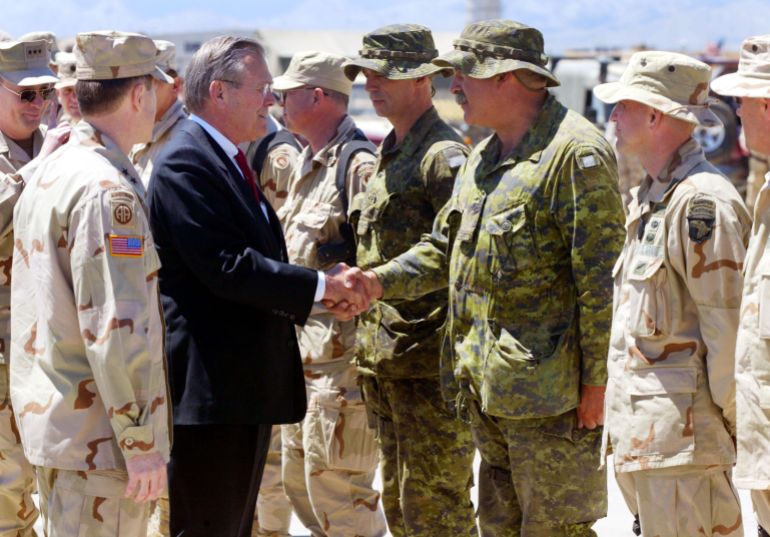 getty_69f30513bd-1777534227 404547 01: United States Secretary of Defense Donald Rumsfeld is greeted by Lt. Col. Pat Stogran (L) and RSM C.W.O. Comeau of the 3 Princess Patricia's Canadian Light Infantry Battalion and others from the coalition forces April 27, 2002 at the Bagram Air Base in Afghanistan. He was visiting the base to thank the troops for their efforts in the war on terror and to talk with Afghan officials about security concerns in the country. (Photo by Joe Raedle/Getty Images)