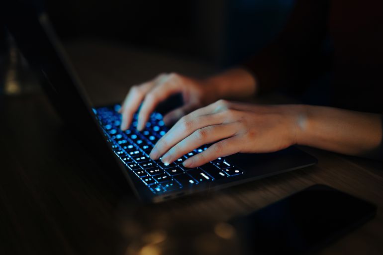 Close-up shot of female hand typing on computer keyboard, using laptop in the dark. Working late. Digital banking. Shopping online. Technology in everyday life. Lifestyle and technology