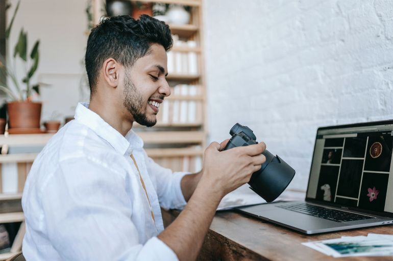 Smiling ethnic male with photo camera near table with laptop Pexels-7129662