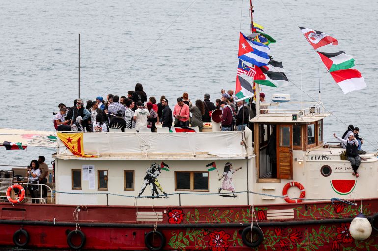 pic-77445-1777514833 People gather on the deck of a painted boat bearing artwork and flying multiple flags as it departs as part of a humanitarian flotilla for Gaza from Barcelona, Spain, April 12, 2026. REUTERS/Nacho Doce
