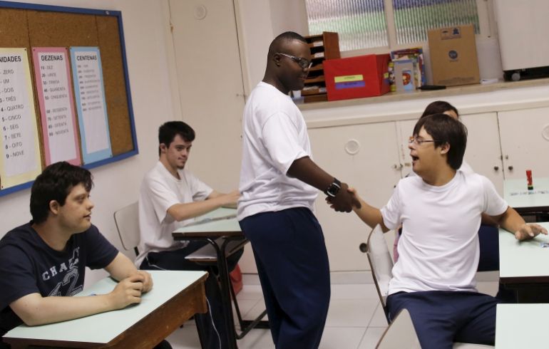 Baker's assistant Edmilson Lourenco, 22, who suffers from down-syndrome, shakes hands with his classmates at the ADID (Association for the Integral Development of Down) school in Sao Paulo March 19, 2015. Edmilson became the first employee with Down Syndrome at the SENAI bakery after winning an internship. He has been attending a special-needs school for the past nine years and his biggest dream is to open his own bakery some day. March 21 is the 10th World Down Syndrome Day which was launched by Down Syndrome International and this year advocates are calling on the world to empower people with Down syndrome. Picture taken March 19, 2015. REUTERS/Nacho Doce