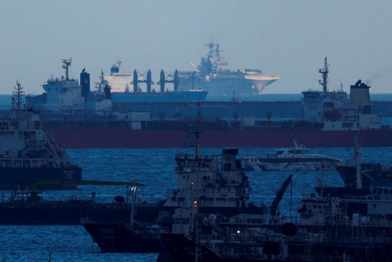 The USS Tripoli (LHA-7) amphibious assault ship, in the background, enters the Singapore Strait, amid the U.S.-Israeli conflict with Iran, as seen from Singapore, March 17, 2026. REUTERS/Edgar Su REFILE - UPDATING TO FIX "STRAITS" TO "STRAIT