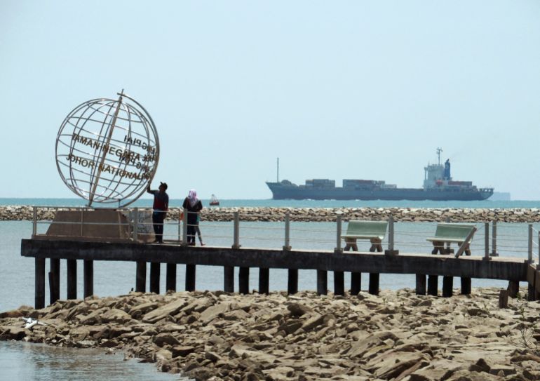 FILE PHOTO: A container ship enters the Singapore Strait for the Strait of Malacca, as tourists stand at mainland Asia's southern most point in Johor, Malaysia November 12, 2016. Picture taken November 12, 2016. REUTERS/Henning Gloystein/File Photo