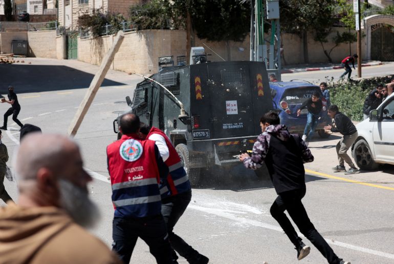 Mourners hurl stones at an Israeli military vehicle amid clashes during the funeral for two Palestinians killed after Israeli settlers and soldiers opened fire, according to witnesses, in Al-Mughayir village near Ramallah, in the Israeli-occupied West Bank, April 22, 2026. REUTERS/Mohammed Torokman